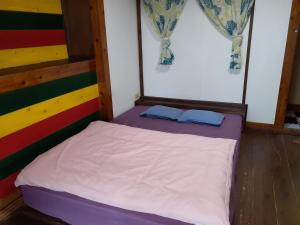 a bed with two blue pillows on it in a room at backpackers guesthouse Border in Nago