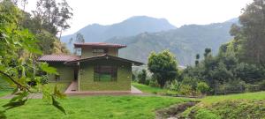 ein kleines grünes Haus mit Bergen im Hintergrund in der Unterkunft "Casa Verde" en Baños de Agua Santa con vista al volcán Tungurahua in Baños