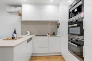 a white kitchen with a sink and a microwave at Little cove gem - walking distance to the most famous Noosa beach! in Noosa Heads +4 photos