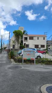 een straat met auto's geparkeerd naast een gebouw bij Haruka 紫 in Naha