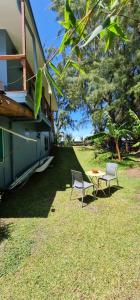 two chairs and a table in the grass next to a house at Pointe Venus Lodge in Mahina