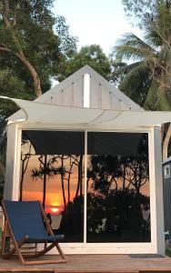 a deck with a chair and an umbrella and a sunset at Walden Koh Lanta - Tiny Homes by the Sea in Ko Lanta