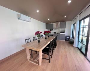 eine Küche und ein Esszimmer mit einem Holztisch und Stühlen in der Unterkunft 373 pool villa in Chiang Rai