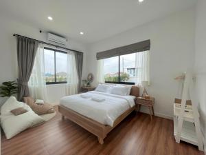 a white bedroom with a large bed and windows at 373 pool villa in Chiang Rai