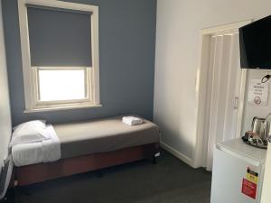 a small bedroom with a bed and a window at Union Club Hotel in Colac