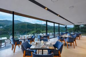 um restaurante com mesas e cadeiras e montanhas ao fundo em Forest Hills Hotel em Soreang