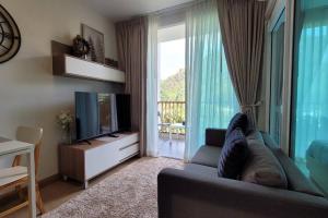 a living room with a couch and a television at Baan Khaoyai cozy in Ban Tha Maprang