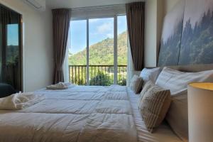 a bedroom with a large bed with a large window at Baan Khaoyai cozy in Ban Tha Maprang