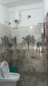a bathroom with a toilet and trees on the wall at Tru Comfort in Puducherry