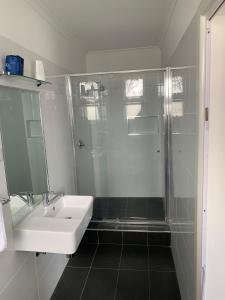 a white bathroom with a shower and a sink at Union Club Hotel in Colac