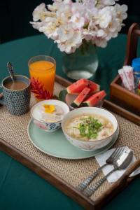 a tray with two bowls of soup and a plate of fruit at โรงแรมมีวาสนา - Me Vadsana Hotel 