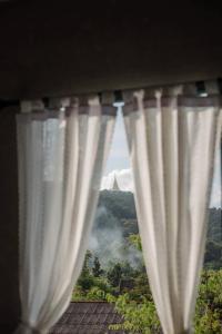a window with curtains with a view of a mountain at โรงแรมมีวาสนา - Me Vadsana Hotel 