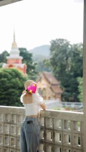 a woman standing on a fence with a pink hat at โรงแรมมีวาสนา - Me Vadsana Hotel 