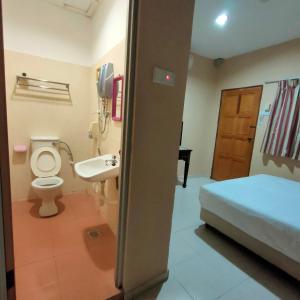 a bathroom with a toilet and a sink and a bed at Kota Lodge in Malacca