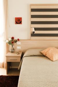 Un dormitorio con una cama y una mesa con un jarrón de flores en Stilhotel, en Signa