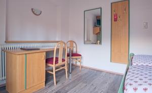 シェッファウ・アム・ヴィルデン・カイザーにあるPension Aloisiaのデスク、椅子2脚、ベッド1台が備わる客室です。