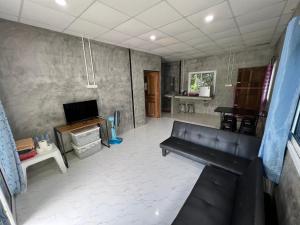 a living room with a couch and a tv at Baan Suan Tondin 