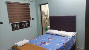 a bedroom with a bed with a blue comforter and a window at Tru Comfort in Puducherry