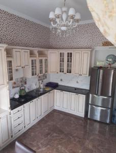 a kitchen with white cabinets and a silver refrigerator at Raffles Villa with pool in Gabala