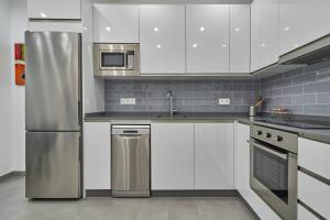 a kitchen with white cabinets and a stainless steel refrigerator at Verano Azul in Nerja