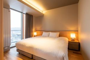 a bedroom with a large bed and a large window at Fenix West in Furano