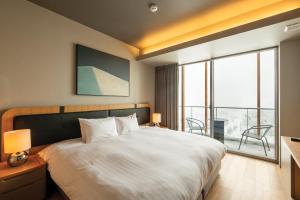 a bedroom with a large white bed and a balcony at Fenix West in Furano +53 photos