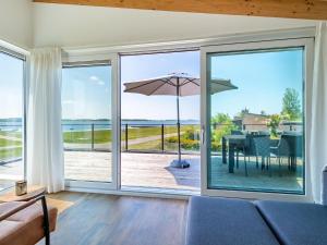 ein Wohnzimmer mit Glasschiebetüren und einem Tisch mit Sonnenschirm in der Unterkunft Elegant Holiday Home in Kamperland next to the Lake in Kamperland