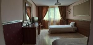 a hotel room with two beds and a desk and a mirror at Hotel Rio in Nova Zagora