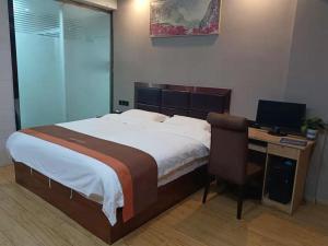 - une chambre avec un lit et un bureau avec un ordinateur dans l'établissement JUN Hotels Jiangxi Yingtan Yujiang County Railway Station Store, à Yingtan