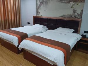 two beds sitting next to each other in a room at JUN Hotels Jiangxi Yingtan Yujiang County Railway Station Store in Yingtan