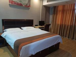 a large bed in a hotel room with a desk at JUN Hotels Jiangxi Yingtan Yujiang County Railway Station Store in Yingtan