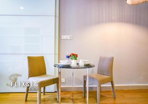 ein Tisch mit zwei Stühlen und ein Tisch mit Blumen darauf in der Unterkunft Flixses Suites at Platinum KLCC in Kuala Lumpur