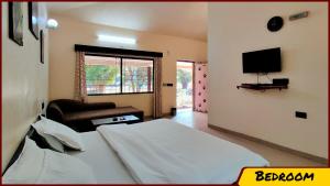a bedroom with a bed and a chair and a television at Kanha Resort in Kānha
