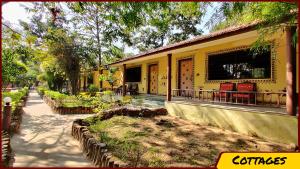 a yellow house with red chairs in front of it at Kanha Resort in Kānha
