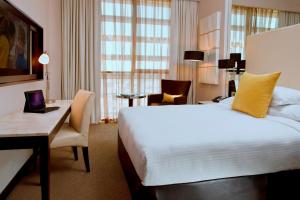 a hotel room with a large bed and a desk at Centro Al Manhal by Rotana in Abu Dhabi