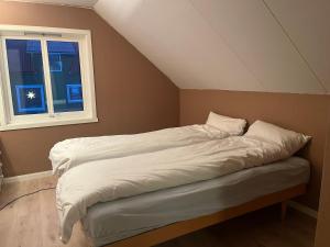 a bed with white sheets in a room with a window at House by the ocean with midnight sun view in Eggum
