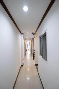 a hallway in a building with white walls and a television at Amber Inn in Bangkok