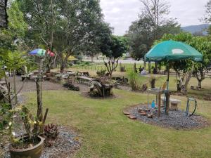 un parque con mesas de picnic y sombrillas en สายฝนการ์เด้น, en Ban On Luai