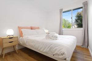 a white bedroom with a bed and a window at Megalong Valley Lookout Cottage in Katoomba
