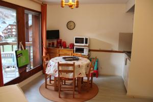 a kitchen with a table with chairs and a microwave at Les Pierres Blanches Contamines Montjoie in Les Contamines-Montjoie