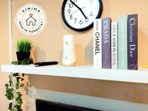 Aimima Muslim Homestay @ Lost World Of Tambun. في Kampong Batu Lapan: رف كتب وساعة على جدار