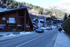 a street in a mountain town with cars and buildings at Les Pierres Blanches Contamines Montjoie in Les Contamines-Montjoie