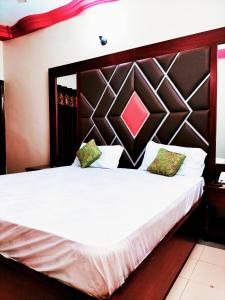 een slaapkamer met een groot wit bed met een groot hoofdeinde bij GULSHAN E IQBAL Guest House Near Mallinum Mall & Agha Khan hospital in Karachi