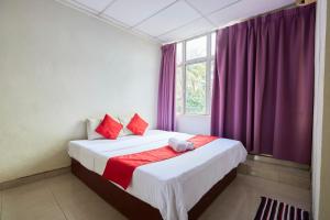 JertihJerteh Hotel, Terengganu的一间卧室配有一张床和一个带紫色窗帘的窗户