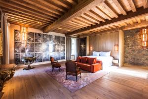 a bedroom with a bed and a couch and chairs at HOTEL Domaine des Etangs in Massignac