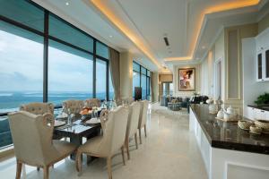 a dining room with a table and chairs and large windows at Panbil Residence Serviced Apartment in Batam Center
