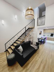 a living room with a black couch and a staircase at Grandera Apart`s - Carbonell 1 in Valencia
