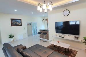 uma sala de estar com um sofá e uma televisão de ecrã plano em Happy Family em Chanthaburi