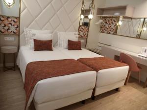 a bedroom with a large white bed and a desk at New Style Lisbon Hotel in Lisbon