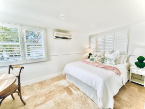 a white bedroom with a bed and two windows at The Boathouse at Whitesands Cronulla in Cronulla